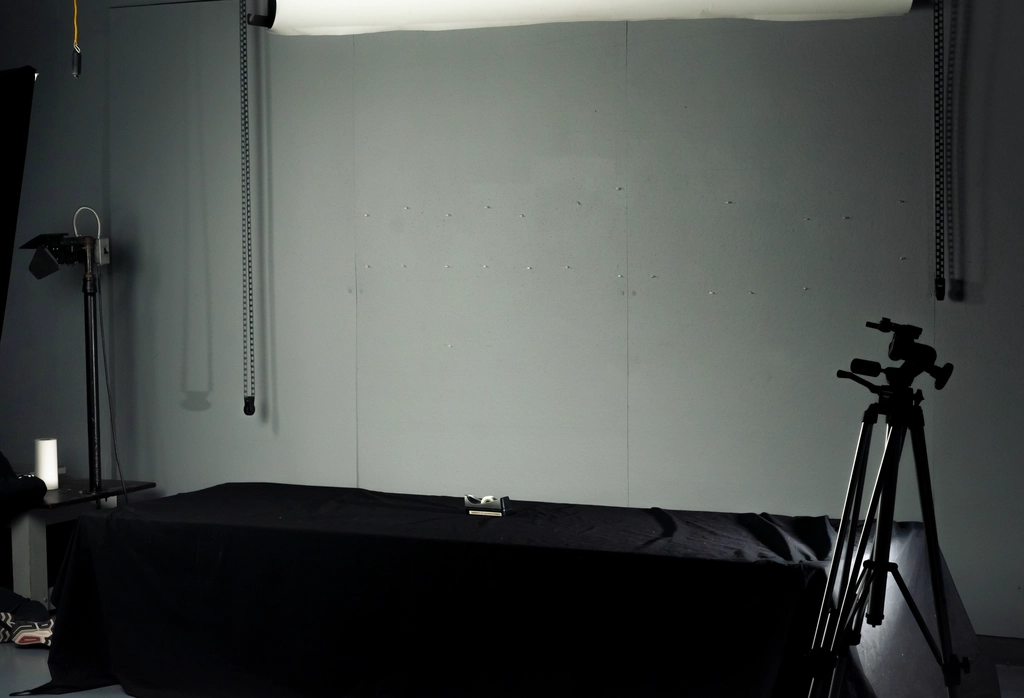 Shooting studio with a small table dispenser on a large black table. A slumped figure is cropped off to the side