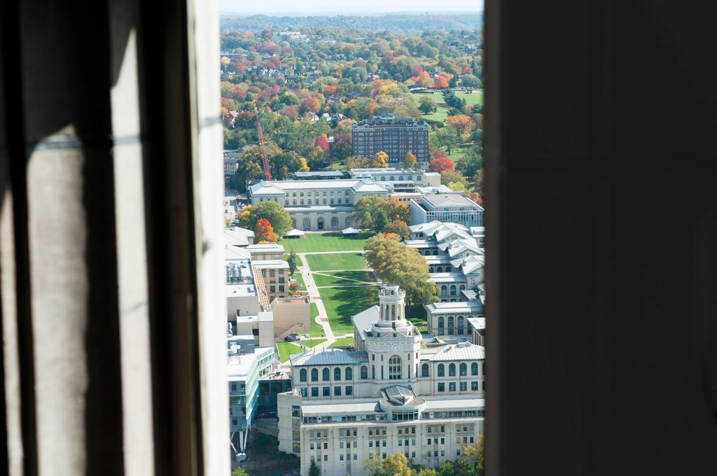 A view of the mall of CMU's engineering building from very high up, as viewed through a concrete window. Assorted colors of fall trees create a nostalgic atmosphere.