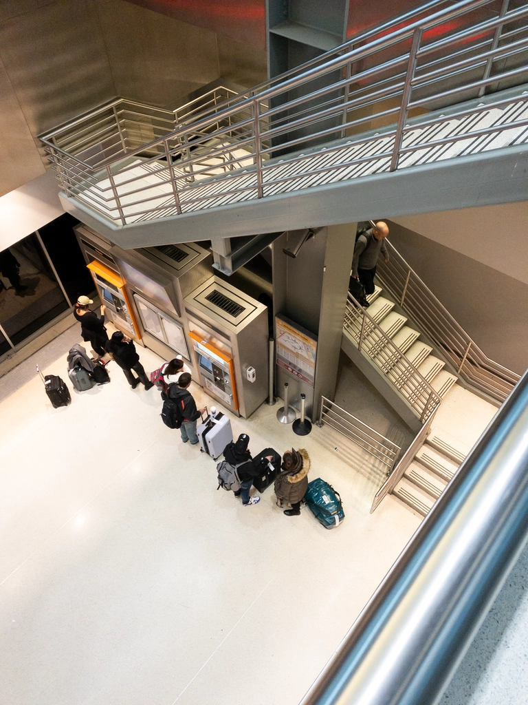 A stairway leads down to where travellers are lined up to buy train tickets