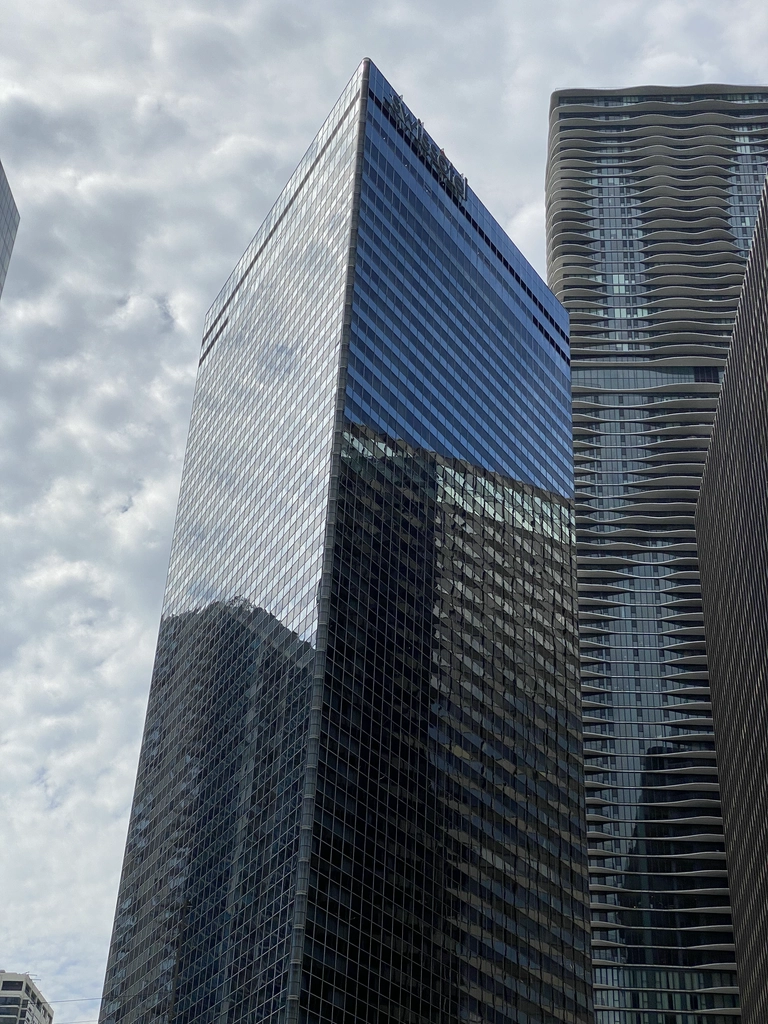 A glassy hotel building reflects the overcast sky and the buildings next to it.