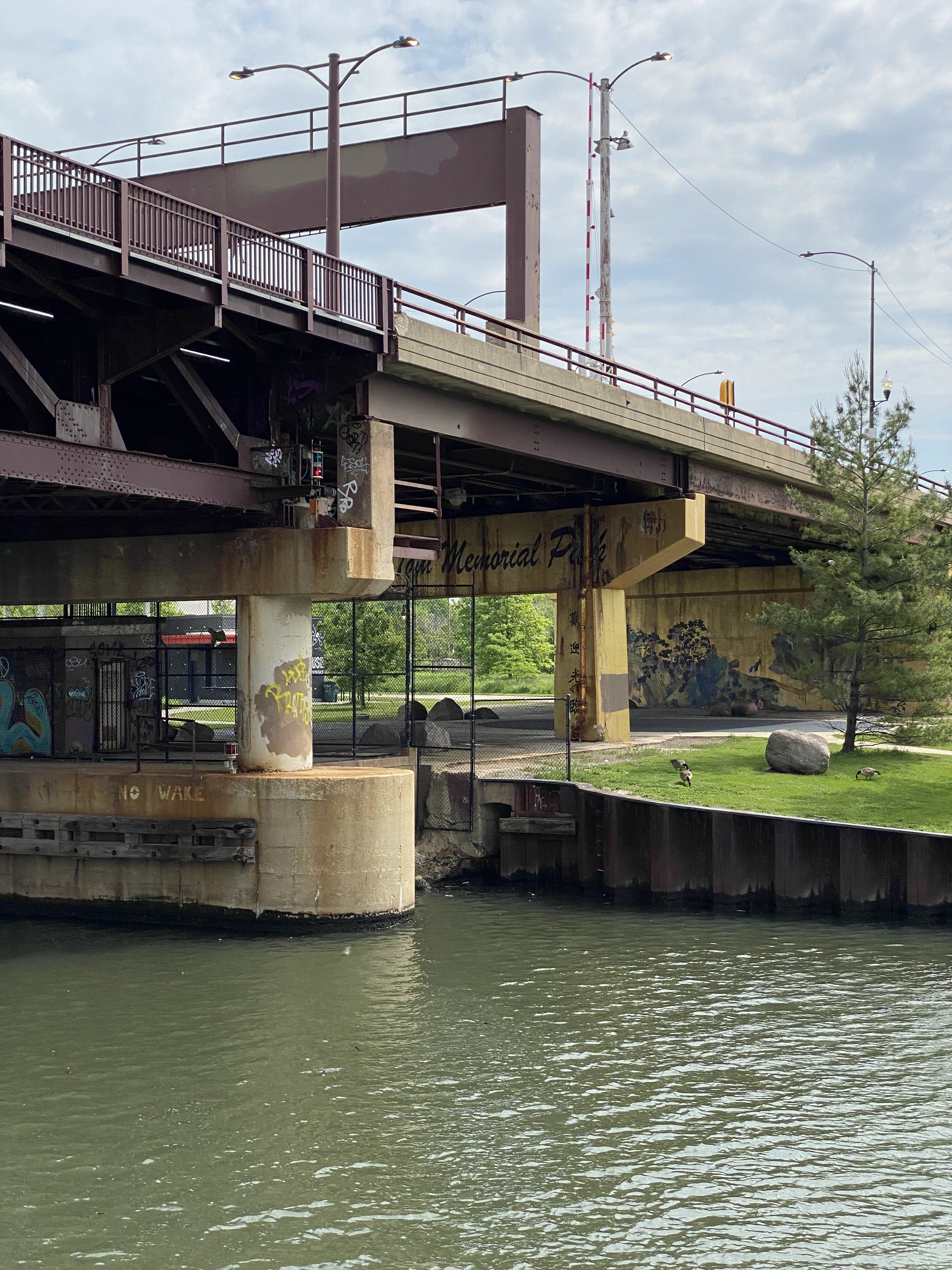 A chinese memorial pavilion beneath a highway. The murals look old.